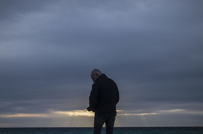 Adult man in winter clothes on beach during sunset. almeria, spain