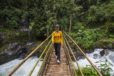 Man standing on footbridge over river