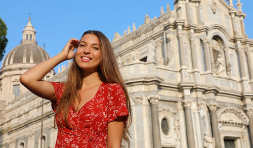 Portrait of smiling young woman against cathedral in city