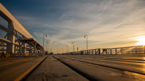 Surface level of bridge against sky at sunset