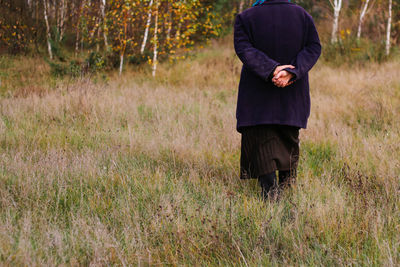 Freedom old woman, female person walking in autumn meadow. fall dry grass. old people leaving home