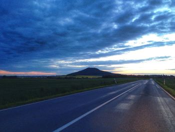 Empty road against cloudy sky