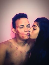 Close-up of young couple kissing against white background