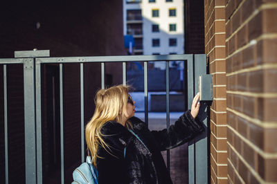 Side view of woman standing by gate