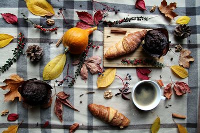 High angle view of coffee with various food and autumn leaves on table