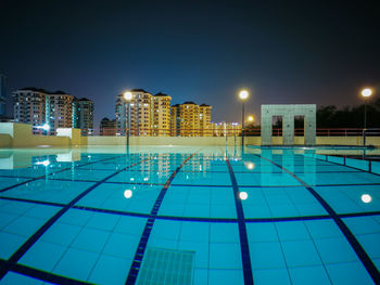 Swimming pool against sky in city at night