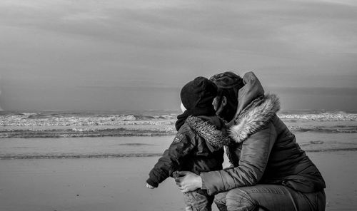 Rear view of couple on beach against sky