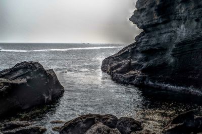 Rock formation on sea against sky