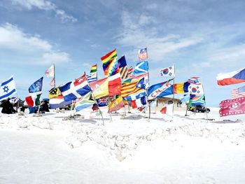 Multi colored flags on deck chairs against sky