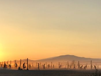 Group of silhouette people on land against clear sky during sunset