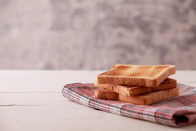 A stack of sliced bread toasts on white wooden background