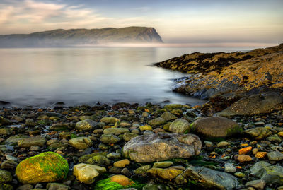 Rocks in sea against sky during sunset