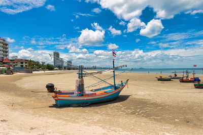 Boat moored on beach against sky