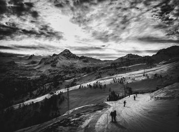 High angle view of silhouette skiers on snowcapped mountain