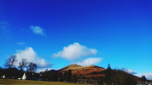 Panoramic view of trees and mountains against blue sky