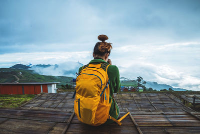 Rear view of man standing on wood against sky