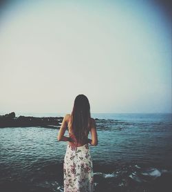 Rear view of woman looking at sea against clear sky