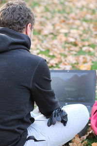 Rear view of man sitting on mobile phone