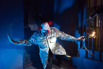 Full length of man holding blue umbrella standing at night