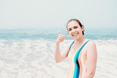 Portrait of young woman standing at beach