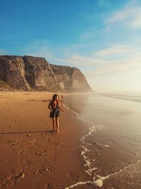 Full length of woman walking on shore against sky