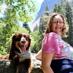 Portrait of woman with dog sitting against sky