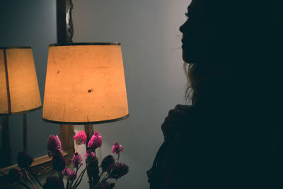 Silhouette woman by illuminated lamp at home