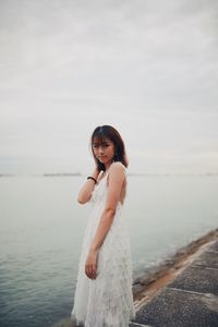 Portrait of woman standing at beach against sky