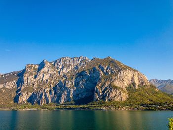 Scenic view of lake and mountains against clear blue sky