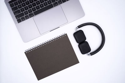 Directly above of spiral notebook with laptop and headphones on gray background