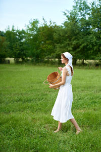 Full length of woman wearing hat standing on field