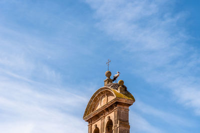 Stork on the belfry of an old church on a blue sky.