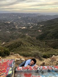 Portrait of woman lying on mountain against sky