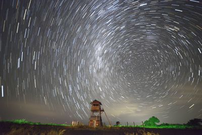 Lookout tower on land against star trails