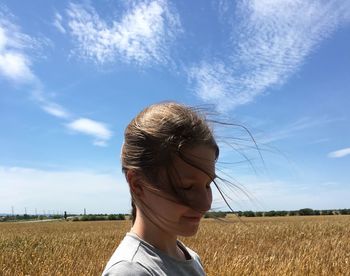 Smiling woman standing on field against sky