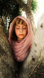 Portrait of cute girl against tree trunk