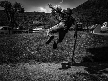 Man jumping on field against sky