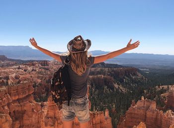 Rear view of woman with arms outstretched looking at rock formations at bryce canyon