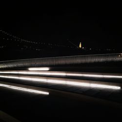 Light trails on illuminated city against clear sky at night