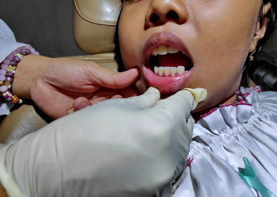 Cropped hands of dentist examining girl