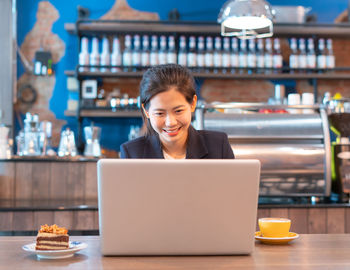 Portrait of mid adult woman using laptop in restaurant