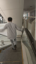 Rear view of woman walking on escalator