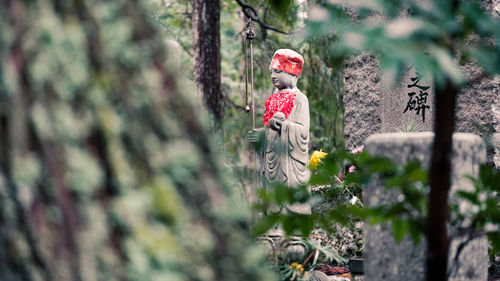 Statue of person by tree trunk