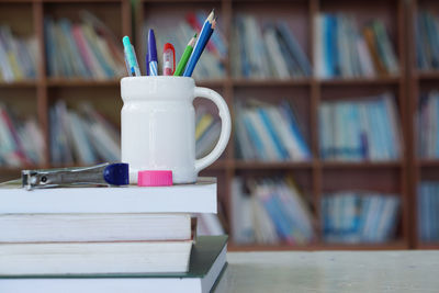 Close-up of books and desk organizer on table in library