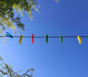 Low angle view of lanterns hanging against clear blue sky