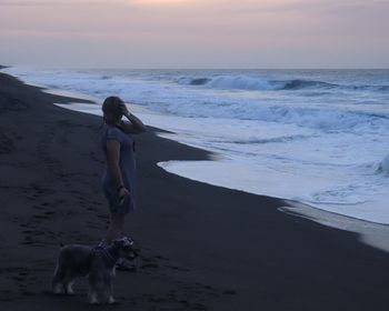 Woman with dog at beach against sky