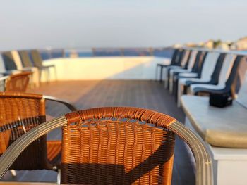 Empty chairs and table at beach against sky