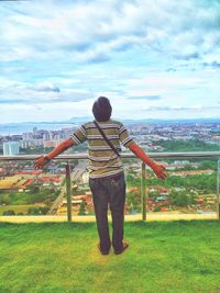 Rear view of man looking at cityscape against sky