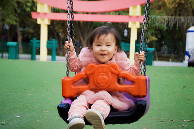 Portrait of cute girl swinging at playground