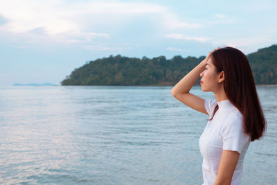 Woman standing in sea against sky